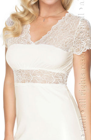 A close-up of a woman wearing the elegant Irall Cameron Nightdress in cream, featuring delicate ivory lace sleeves and a lace overlay on the bodice. She has blonde, wavy hair, and the image shows her from shoulders to waist without revealing her face. Text is partially visible along the right edge.