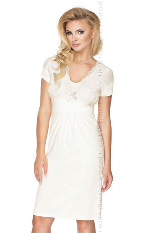 A woman with blonde hair is wearing the elegant Irall Gia Cream Nightdress, which features short sleeves, delicate viscose lace detailing on the bodice, and a small bow at the waist. The nightdress has a knee-length hemline, and she is posing against a white background.