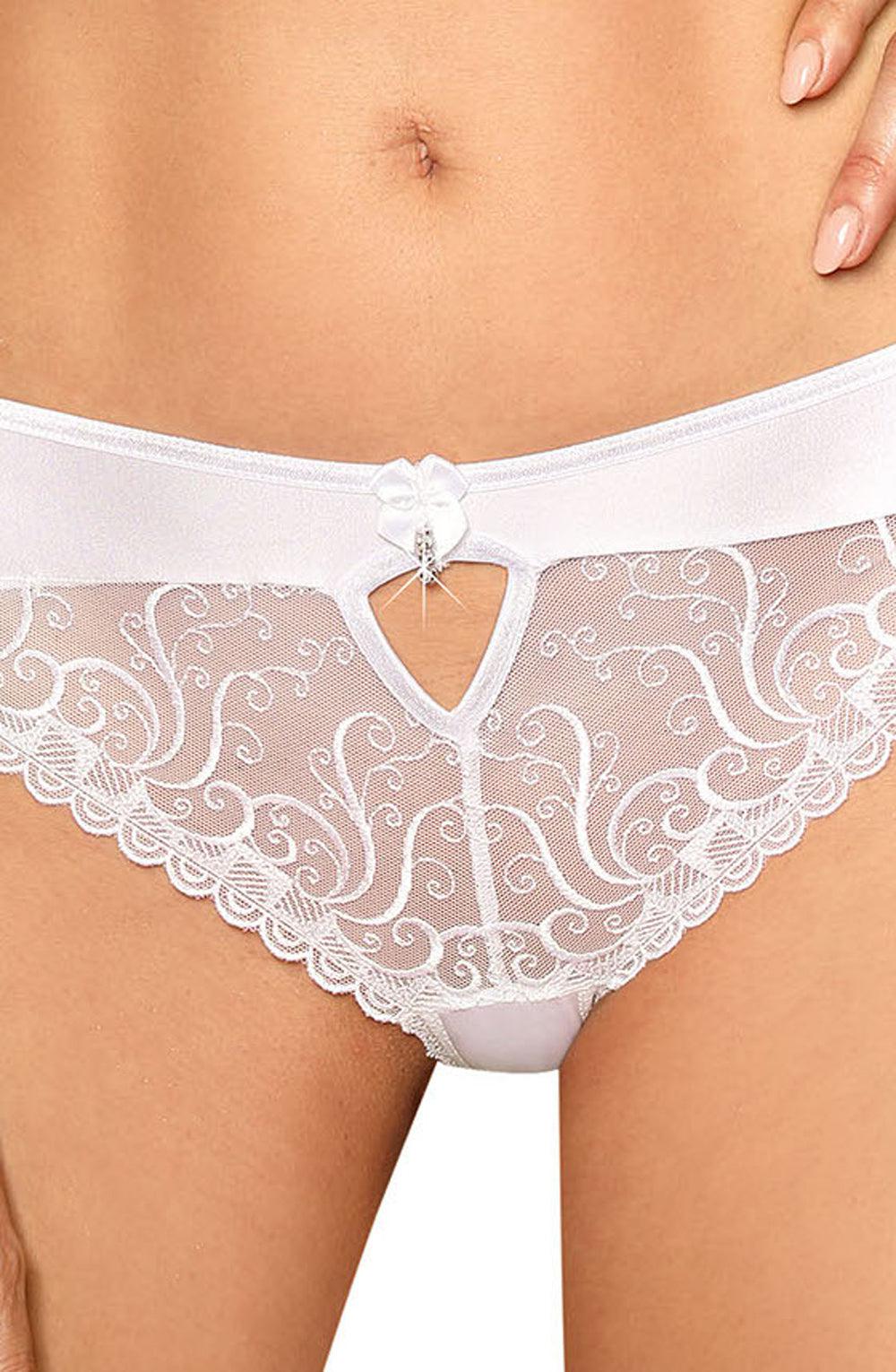 Close-up of a person wearing the elegant and luxurious Roza Anuk Brief White by Roza. The intricate, swirled lace pattern with scalloped edges features embroidered details. A small flower and jewel adornment graces the center of the waistband above a keyhole cutout. The person's hand rests on their hip.