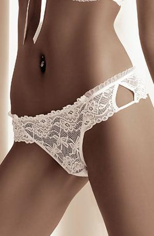 A close-up image of a woman's midsection, showcasing the Roza Carmen White Thong with its intricate lace patterns and a cut-out detail on the hip. The background is softly blurred and light in color, enhancing the elegance of the piece.