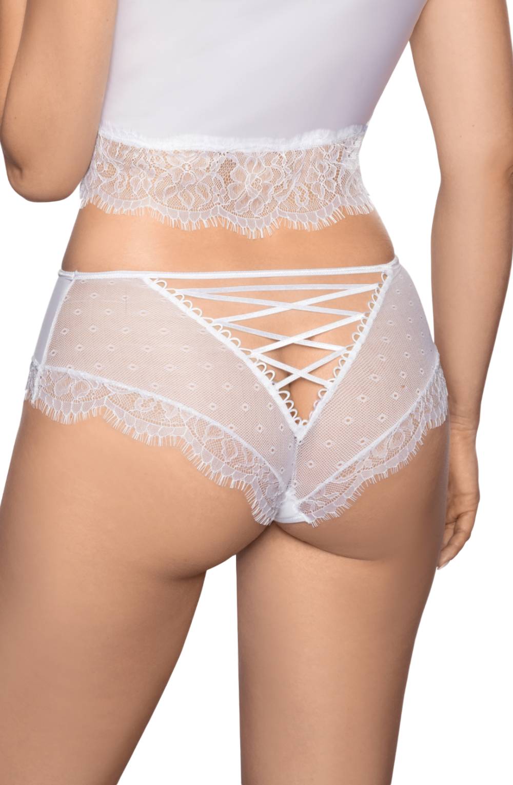 A person is seen from the back, wearing luxurious lace lingerie crafted with premium stretch fabric. The semi-sheer Roza Erii White Brief by Roza features a delicate lace trim and crisscross ribbon design on the back. The look is completed with a matching lace-trimmed white top.