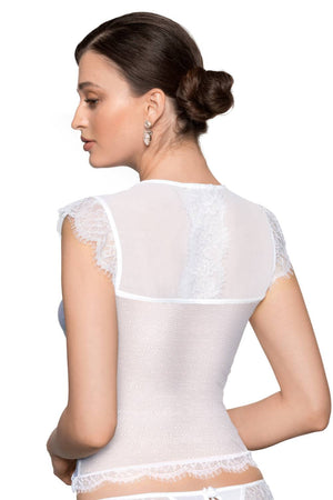 A woman with her hair styled in a low bun is shown from the back, wearing the Roza brand's Erii White Shirt. The top features intricate eyelash lace details on the back and shoulders, paired with matching lace trim on the bottom edge. She accessorizes with large, dangling earrings.