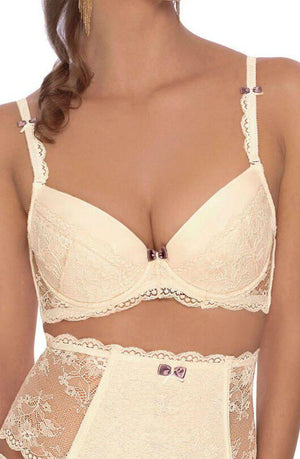 A woman is wearing a matching set of ivory-colored lingerie, featuring the elegant Roza Fifi Push Up Bra and high-waisted lace panties. Both the bra and panties are embellished with small purple bows. Her hair cascades in loose curls, complemented by her long, dangling earrings.