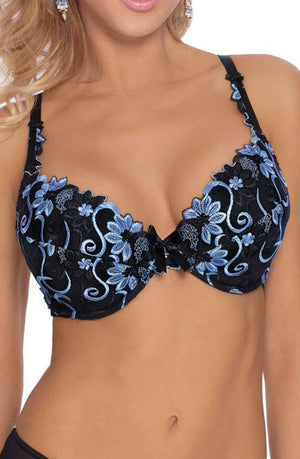 A person is modeling the Roza Florence Blue Bra, a luxurious piece of lingerie from the brand Roza. It is adorned with intricate blue floral embroidery and features adjustable straps, removable push-up pads, and a black bow in the center. The person's face is not visible in the image.