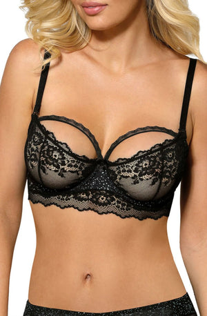 A woman wearing the Roza Kena Black Soft Cup Bra, known for its intricate floral patterns and semi-sheer design, showcases its elegant lingerie appeal. She has blonde, wavy hair cascading around her shoulders, with a plain white background emphasizing the exquisite floral lace of the bra.