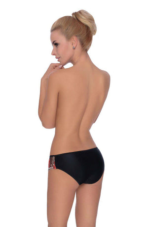 A person with blonde hair tied up in a bun is standing with their back to the camera, looking over their shoulder. They are wearing the Roza Natali Black Brief by Roza, which features colorful floral embroidery on the side. The background is plain white.