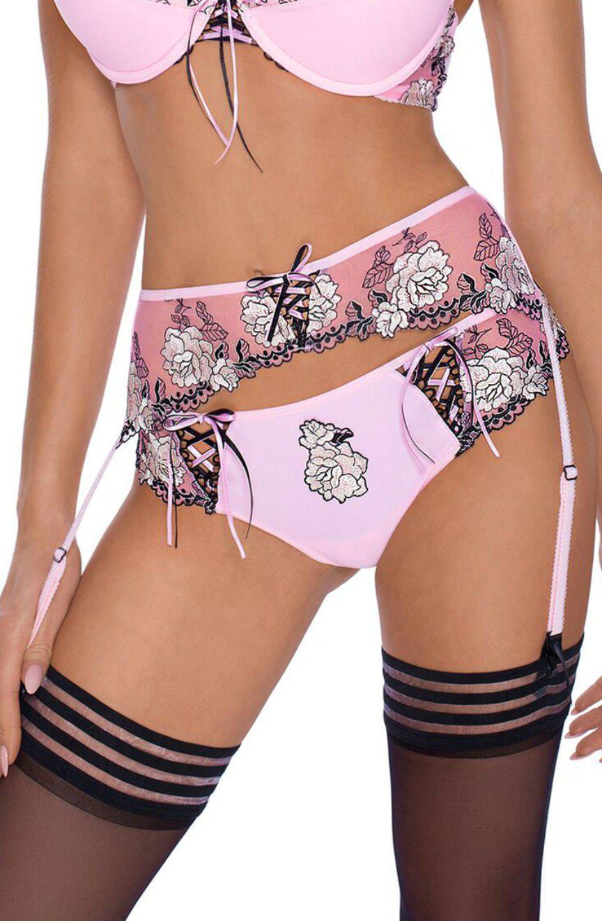 A person wearing a set of Roza Natali pink and black lingerie with floral embroidery and lace-up detailing. The ensemble, which includes a bra, garter belt, and matching panties by Roza, is complemented by black thigh-high stockings featuring horizontal stripes at the top.