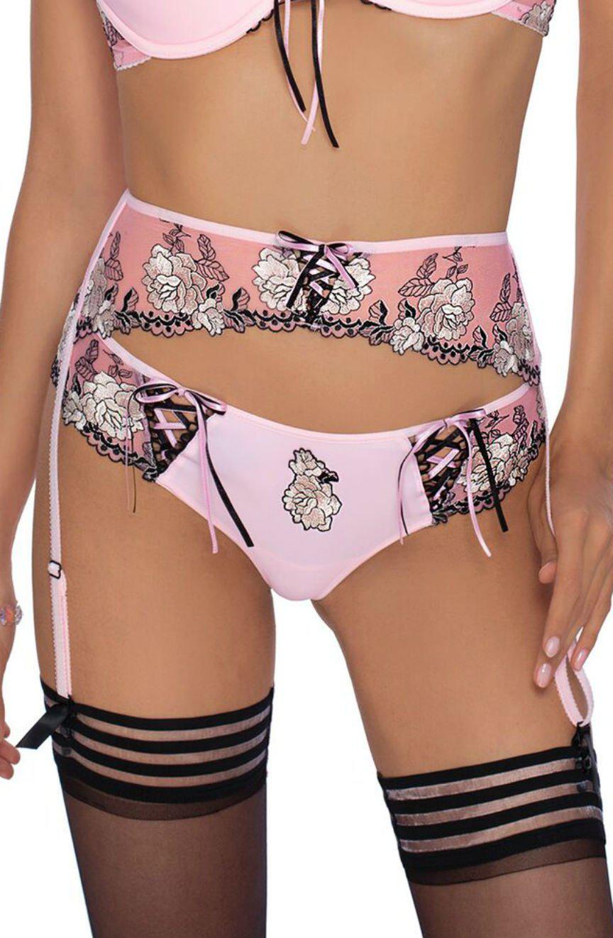 A person is wearing the Roza Natali Pink Suspender Belt adorned with black lace floral embroidery. The ensemble includes a bra, panties with lace-up detailing, a matching garter belt, and black thigh-high stockings with pink garters from the Roza box collection. The person's face is not visible in the image.