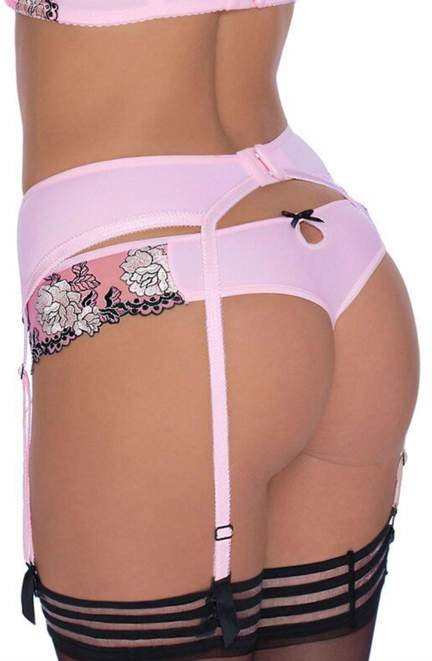 A person is wearing the Roza Natali Pink Thong from the Roza collection, which includes a garter belt adorned with black lace trim and floral embroidery. The ensemble is paired with black thigh-high stockings. The back of the lingerie features a small keyhole cutout and decorative bows.