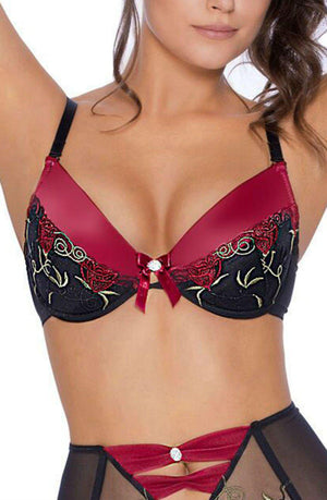 A woman models the Roza Rufina Push Up Bra Black by Roza, showcasing its deep red and black color scheme with intricate lace detailing, soft push-up cups, and small decorative bows. The bra is designed with a black lace overlay and floral embroidery, while the matching bottoms are partially visible featuring a similar design.