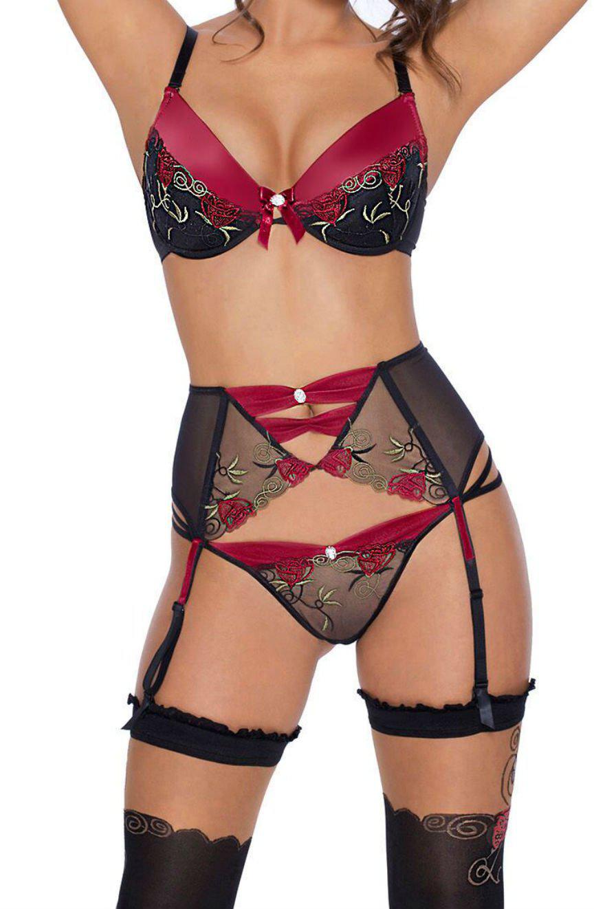 A person is modeling a matching lingerie set, featuring the Roza Rufina Push Up Bra in Black by Roza, adorned with floral embroidery and soft push-up cups. The ensemble includes a high-waisted mesh suspender belt with complementary floral embroidery and stockings fastened by black garters. Their head and legs are partially out of the frame.