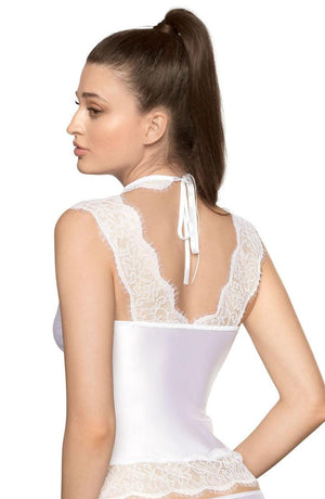 The image shows a woman with long brown hair styled in a ponytail, wearing the Roza Sija White Shirt by Roza. The top features white satin and eyelash lace with a halter neck that ties at the back with a white ribbon. She is facing away from the camera, showcasing the intricate lace detailing on the back of the shirt.