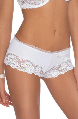 A person is wearing delicate white lace lingerie. The focus is on the lacy Roza Sisi White Shorts boyshort-style panties with decorative lace trim and a small bow accent on the side. The top part of the matching Roza Sisi White Bra is partially visible. The person is holding a small object.