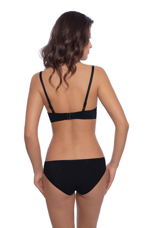 A woman with wavy brown hair is seen from behind, wearing a black bra and matching Roza Vangelise Brief in black, featuring a stretchy waistband. She stands against a white background, with her arms relaxed by her sides.